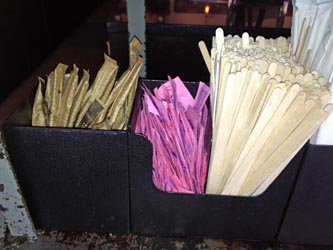 Tubes of sugar, pink packets, swizzle sticks