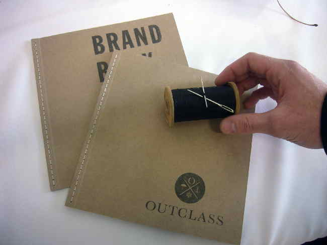 Tan-coloured Outclass brand books, plus needle and thread