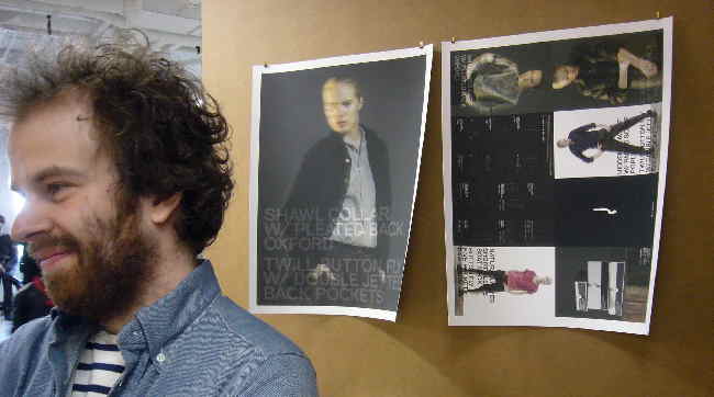 Bearded, scraggly-haired Markus before two printouts of his ad campaign