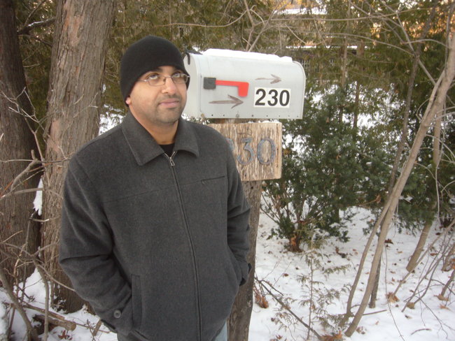 Man in toque outside rural-looking mailbox