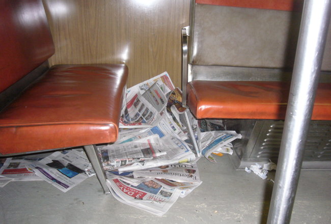 Large pile of newspapers under H4 subway-car seat