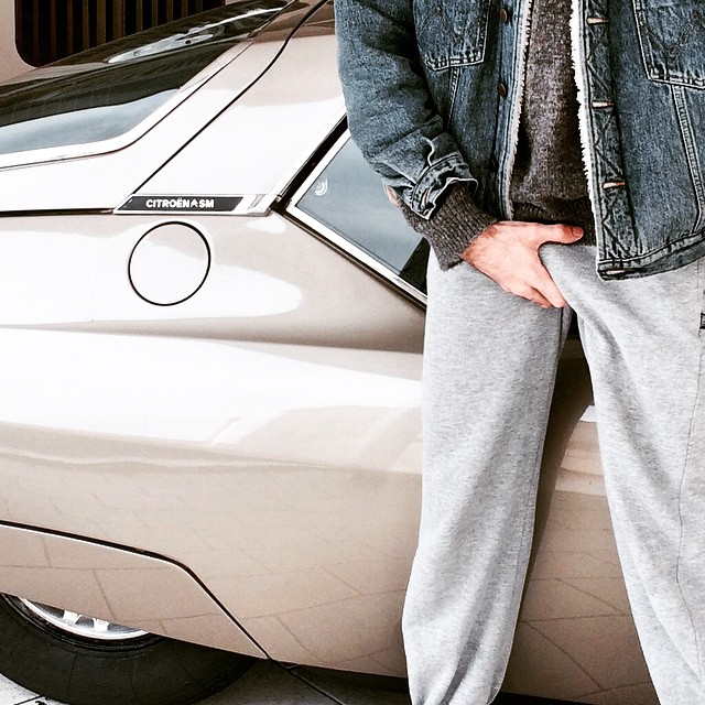 Man grabbing wang through sweatpants in front of Citroën SM