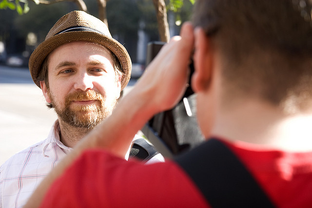 Scott (with beard and in hat) has his picture taken by man out-of-focus in foreground