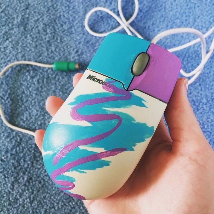 Microsoft PS/2 mouse with teal left button, magenta right button, and magenta swirl on teal background on mouse body