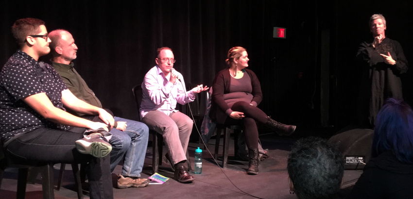 Four panellists, one speaking into microphone, with interpretrix