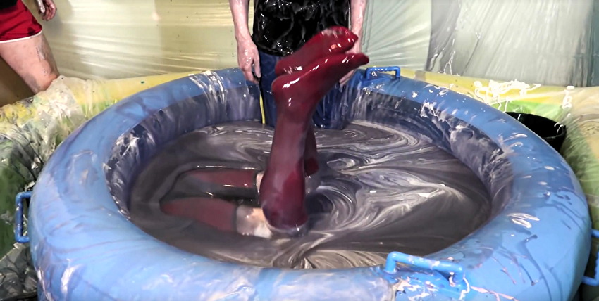 Man’s red-clothed legs stick straight up out of a small pool of wirly-surfaced slime