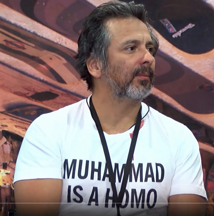 Somewhat-grey-haired Hispanic in MUHAMMAD IS A HOMO T‑shirt