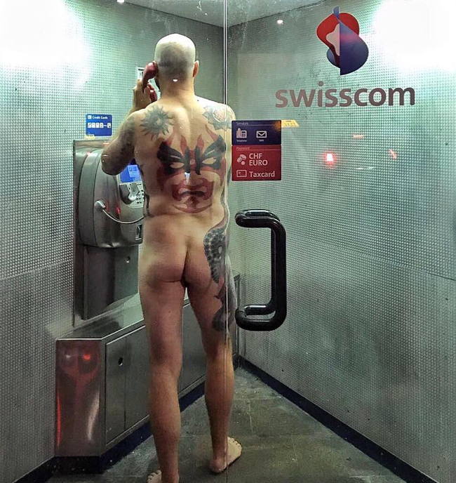 Tattooed man naked in Swiss phone booth