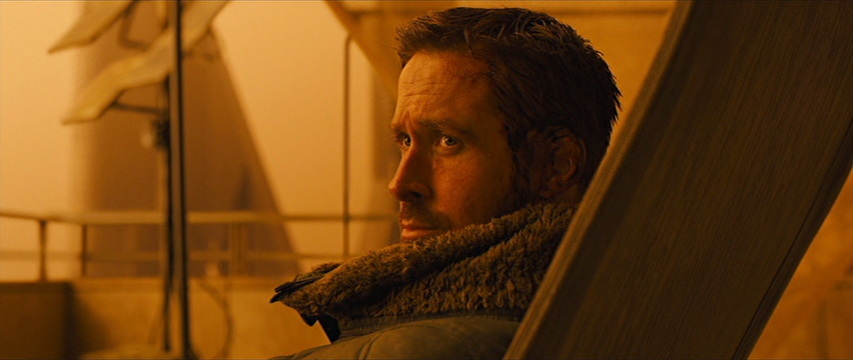 Amber-tinted scene shows R. Gosling turning his head to the left, tall fur-like collar folded slightly